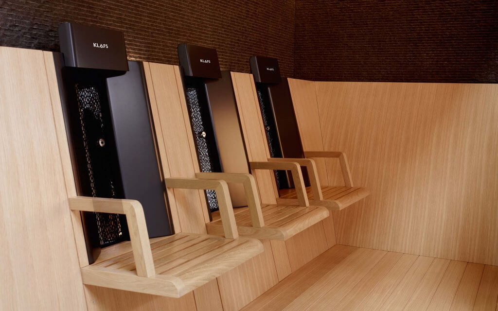 Three infrared chairs positioned against a wooden wall in an infrared cabin