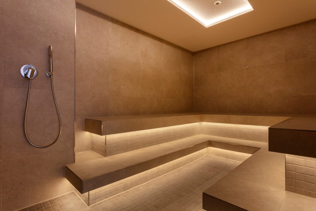 A contemporary steam room featuring a sleek shower and a stylish bench, designed for relaxation and comfort.